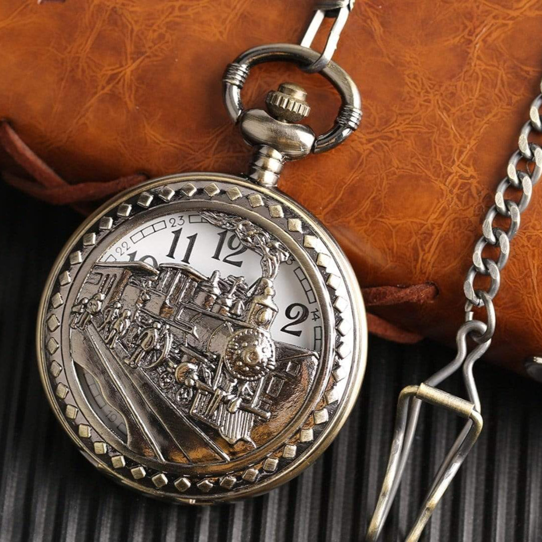 Close-up of a bronze-colored, train-themed pocket watch with a chain.
