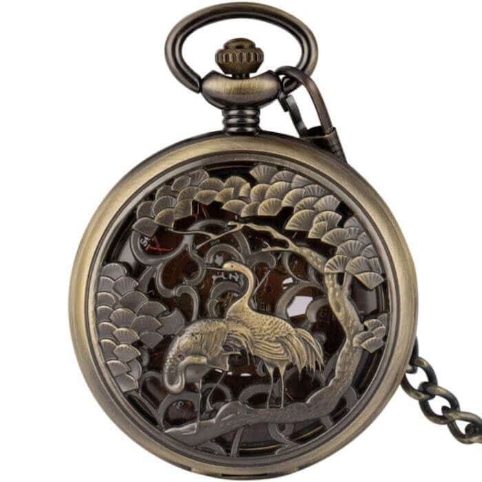 Bronze-toned pocket watch with openwork design depicting a crane and an elephant under a tree. 
