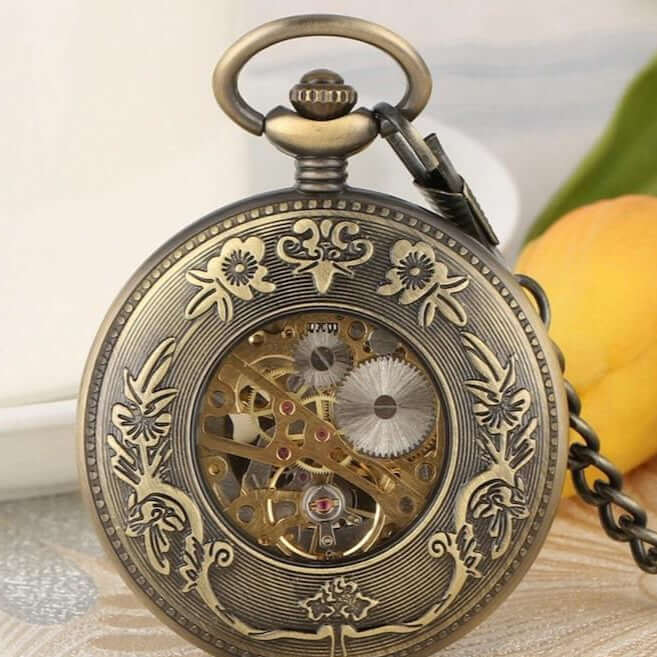 Close-up of a bronze pocket watch with an intricate, open-face design showing the inner workings of the clock.