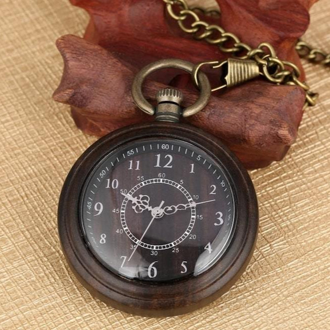 Antique wooden pocket watch on display with chain and stand.