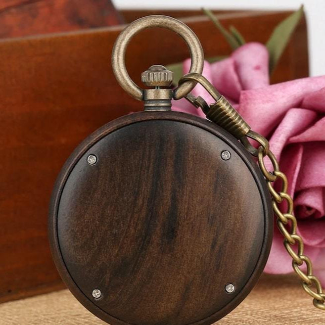 Close-up of a wooden pocket watch with a bronze chain. 
