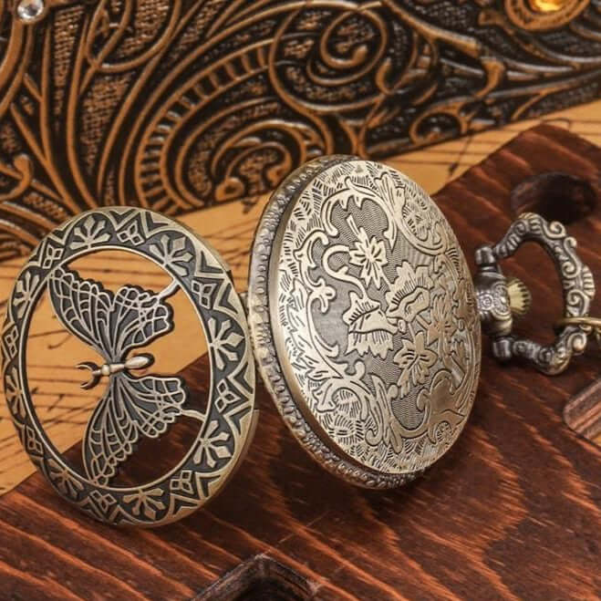 Ornate brass pocket watch with butterfly and floral design.
