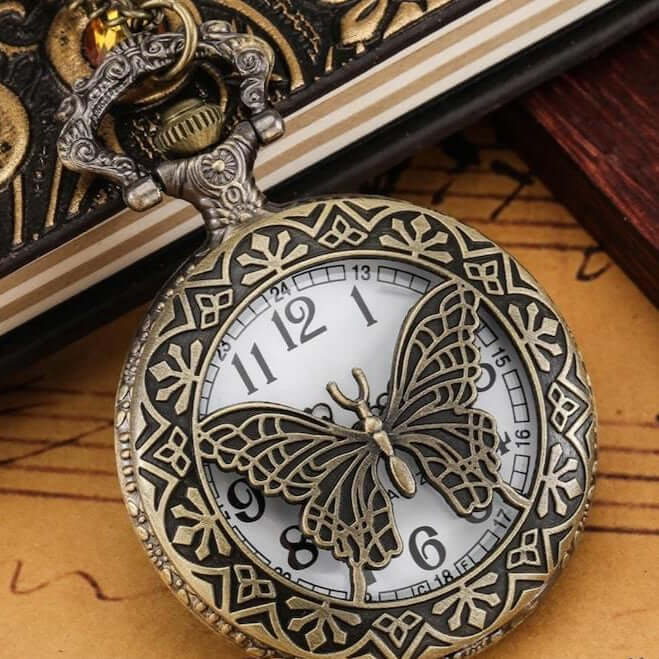 Antique bronze pocket watch with butterfly design.