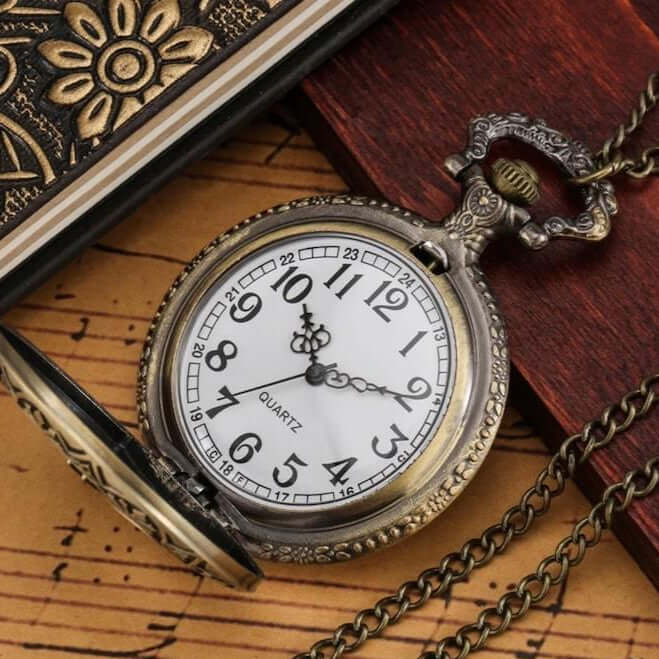 Close-up of an open, antique pocket watch with chain, on a wooden surface.