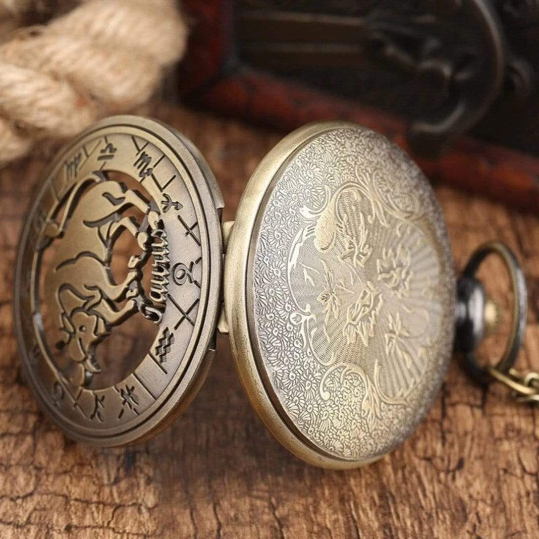 Open brass pocket watch with Taurus zodiac symbol and floral pattern.
