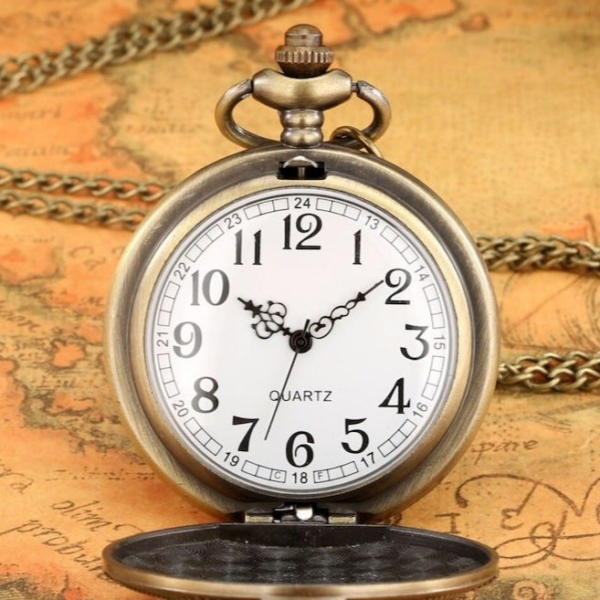 Close-up of an antique brass quartz pocket watch with a white face and a chain, displayed on a map.