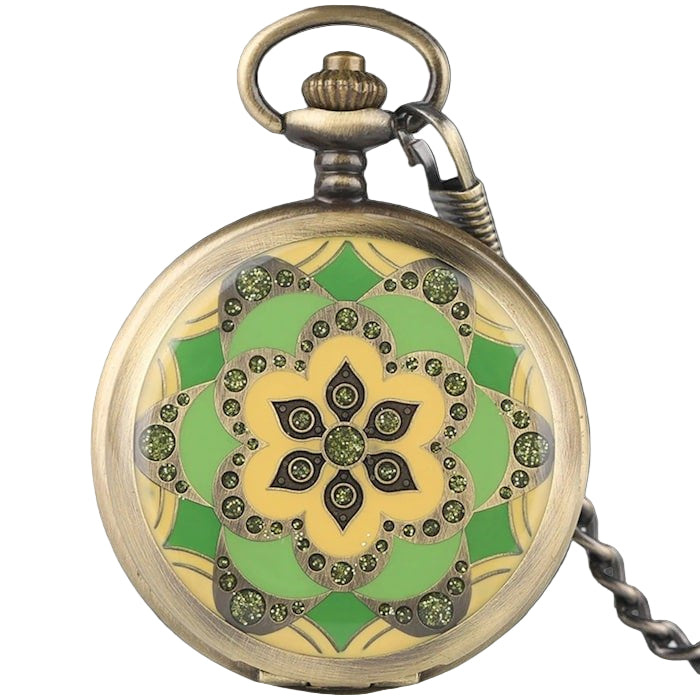 Round brass pocket watch with a green and yellow flower design.
