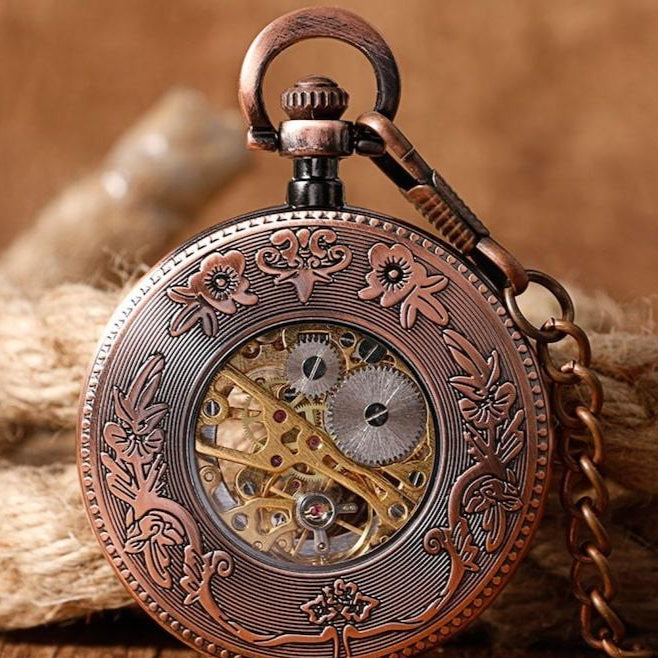Copper-colored pocket watch with a visible mechanism and ornate floral carvings.