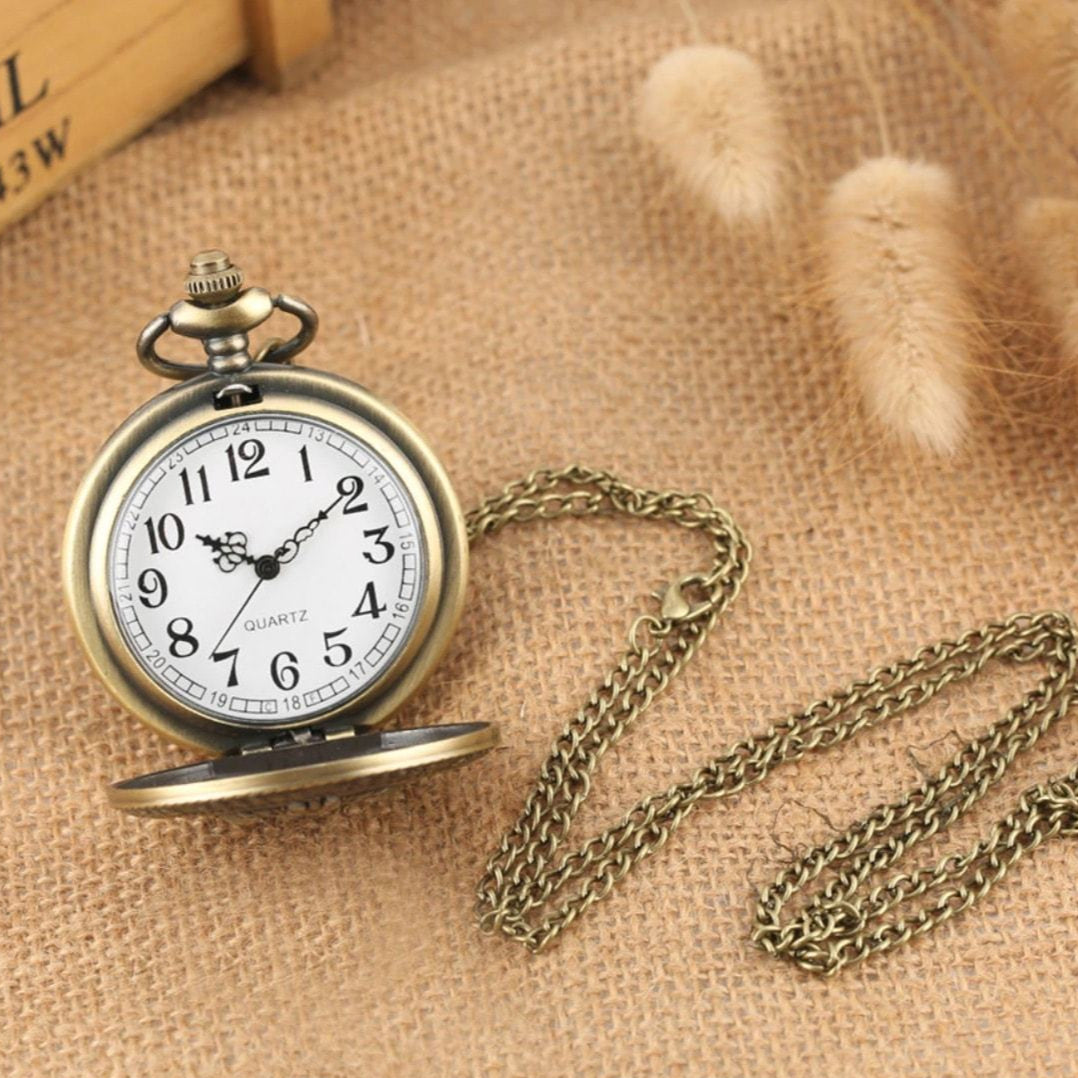 Antique bronze pocket watch with chain on burlap.
