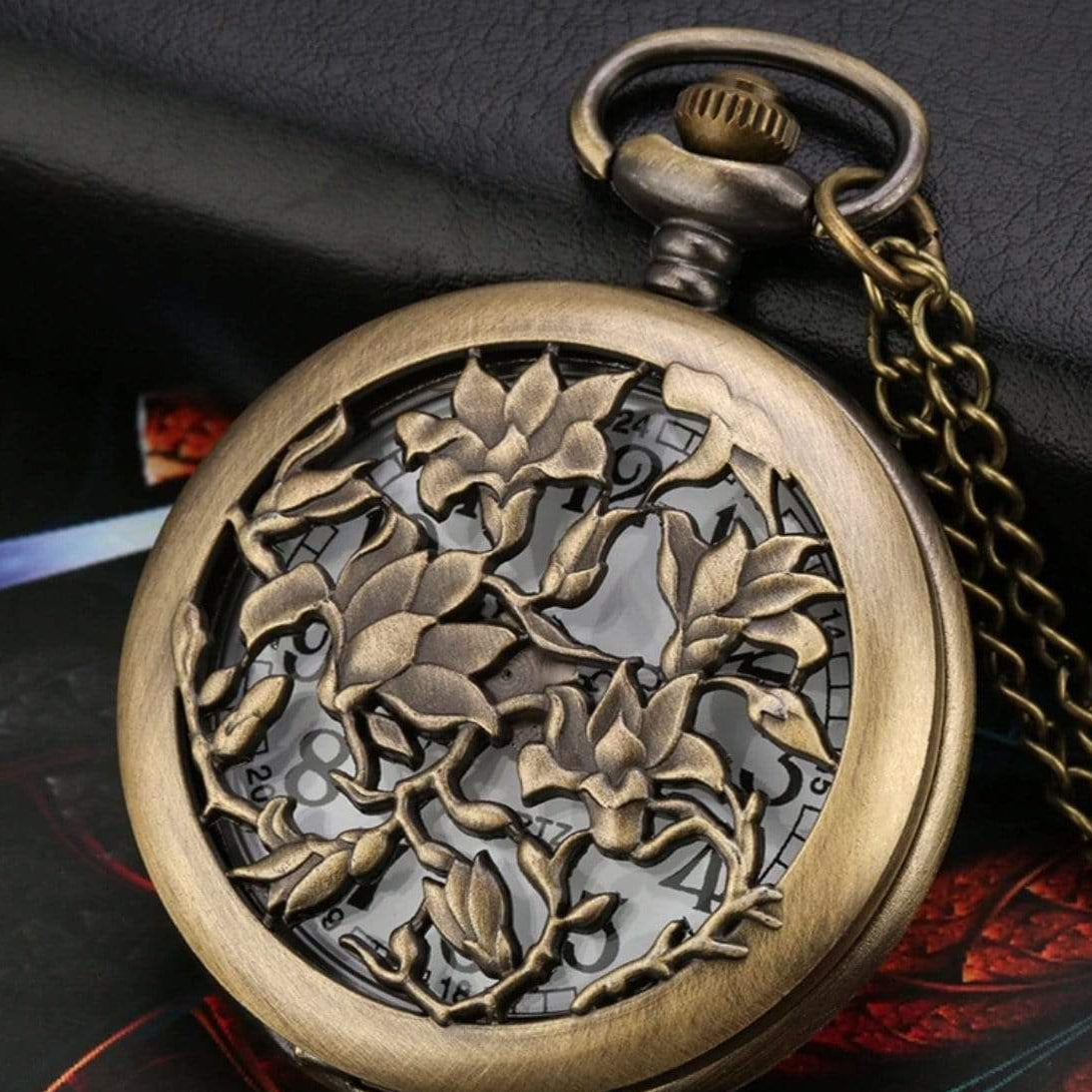 Close-up of bronze pocket watch with floral design and chain.
