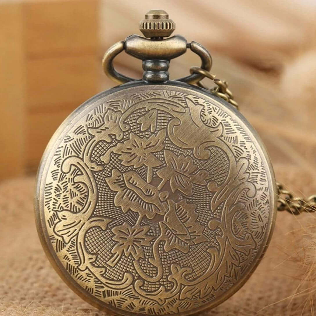 Close-up of a bronze-colored pocket watch with an intricate floral pattern on its case.