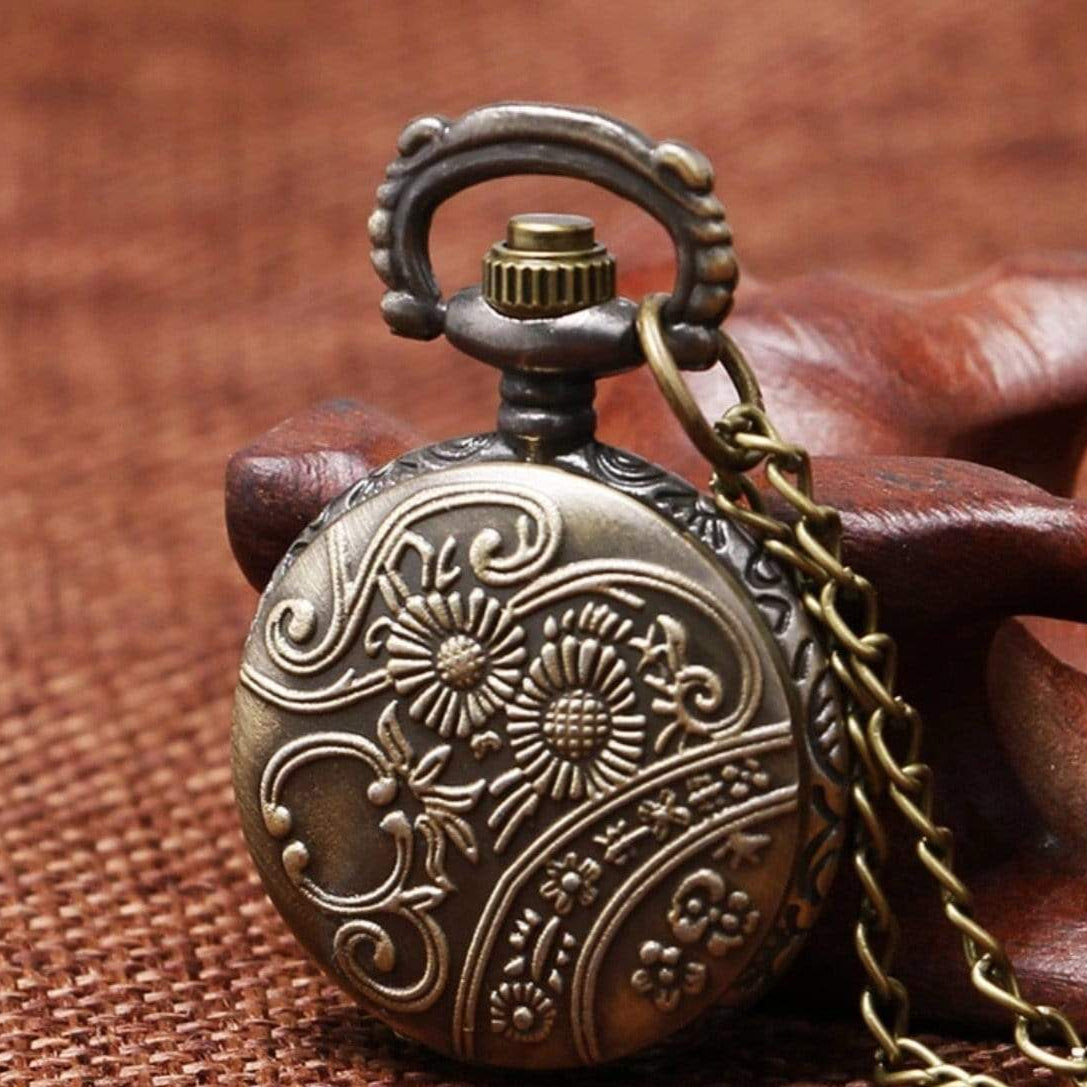 Bronze pocket watch with floral design and chain.

