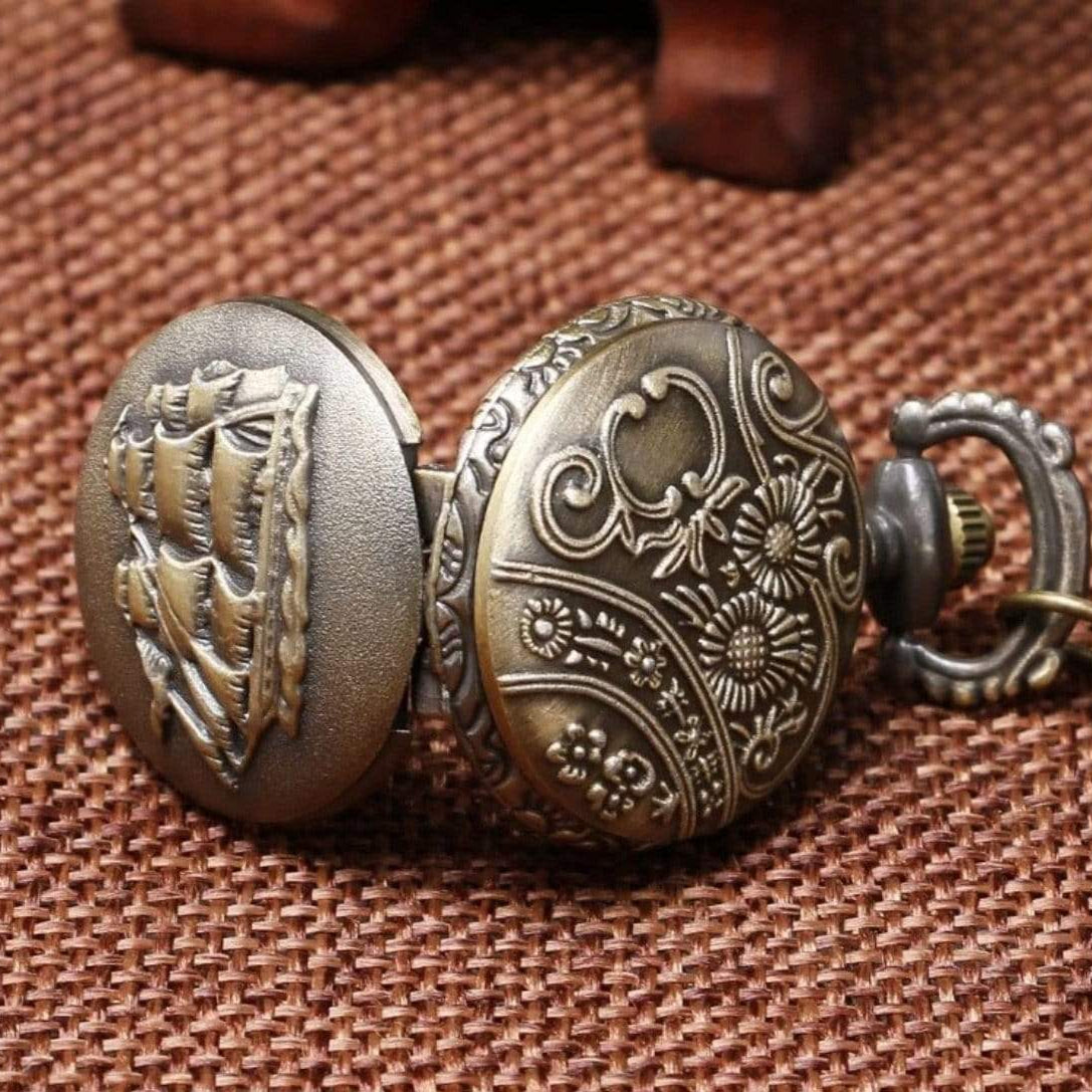 Antique bronze pocket watch with nautical and floral designs.
