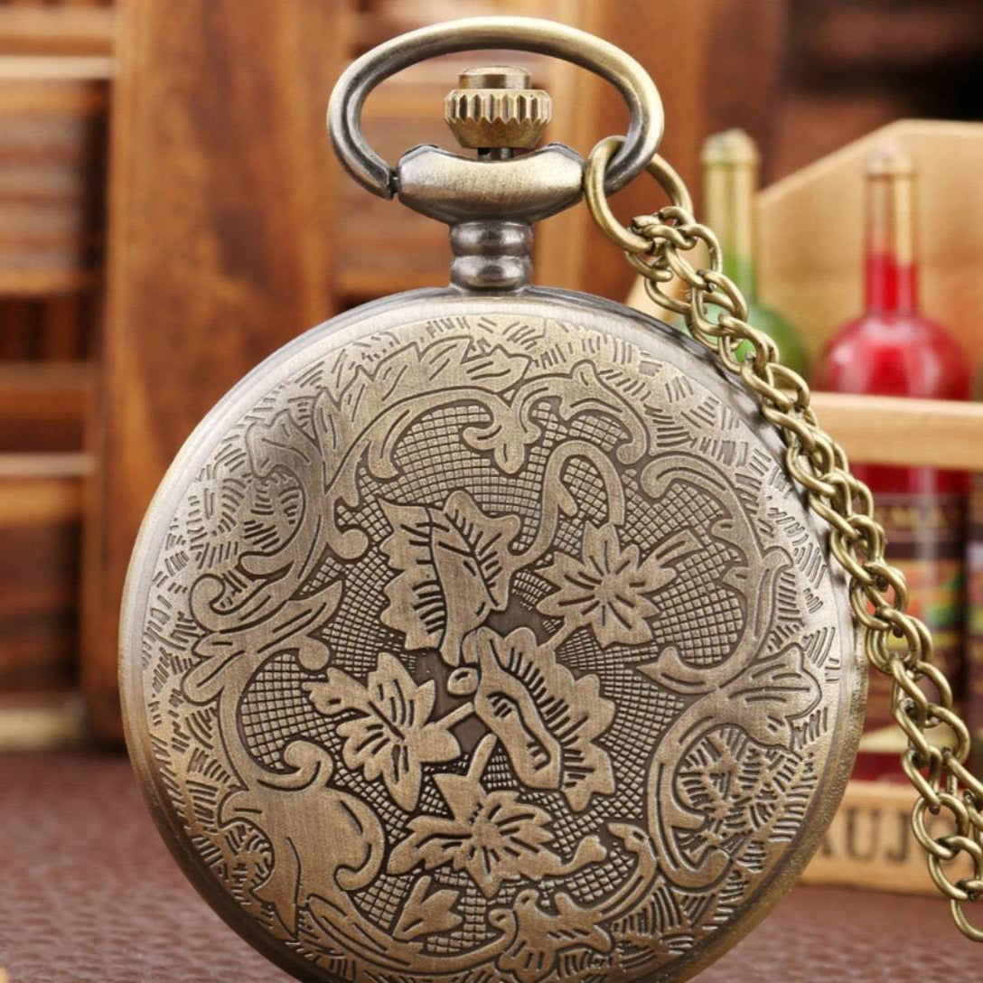 Close-up of an ornate antique brass pocket watch with chain.
