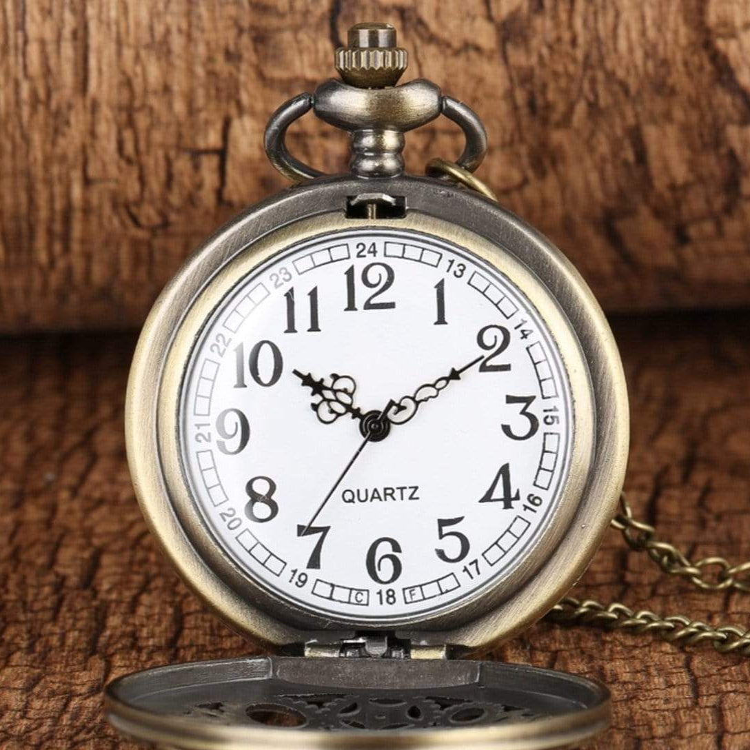 Close-up of an open, bronze-colored pocket watch with a white face against a wooden background.