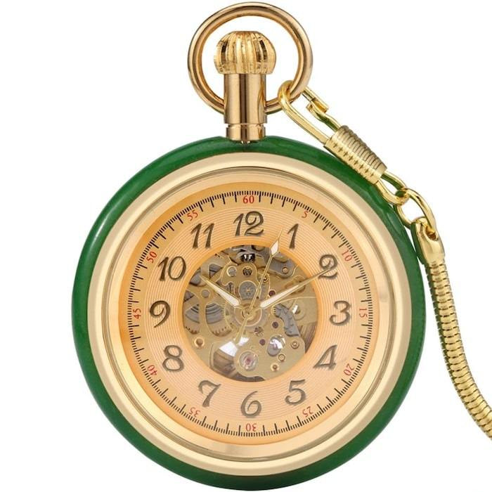Close-up of a green and gold pocket watch with visible gears and a snake chain.