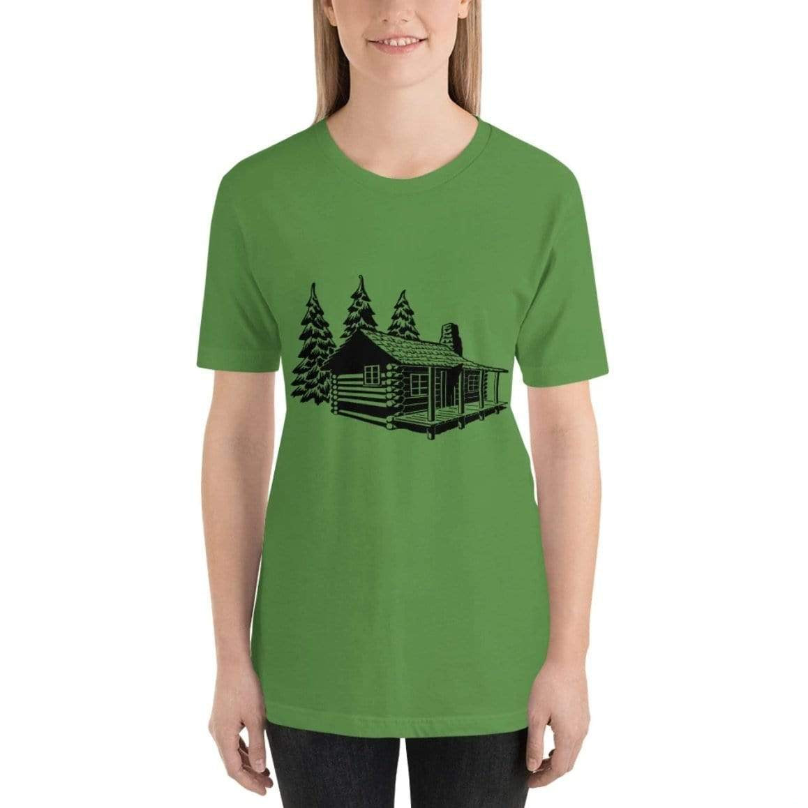 Woman wearing a green t-shirt with a cabin and trees design and dark pants.